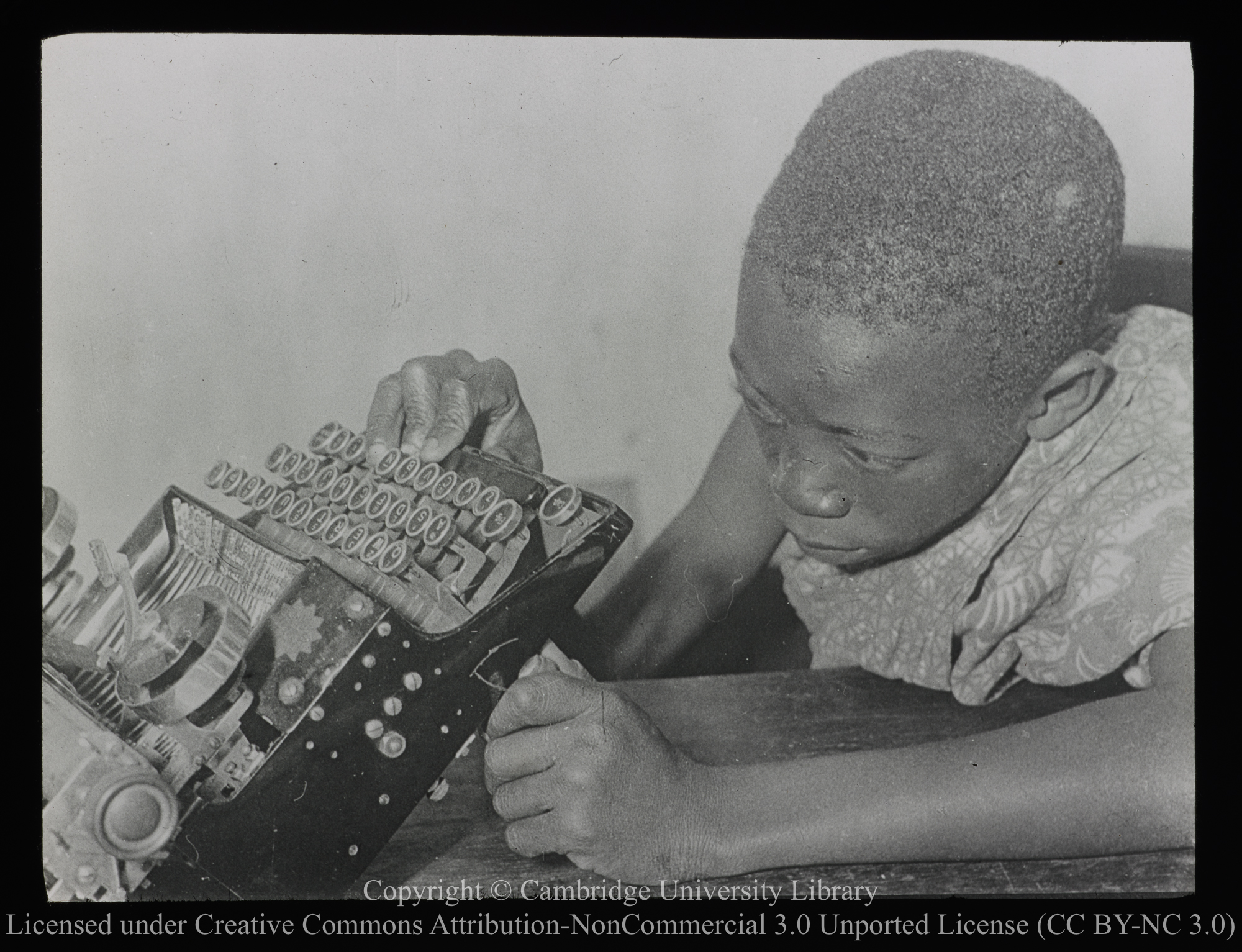 Young African examining typewriter, 1900 - 1947