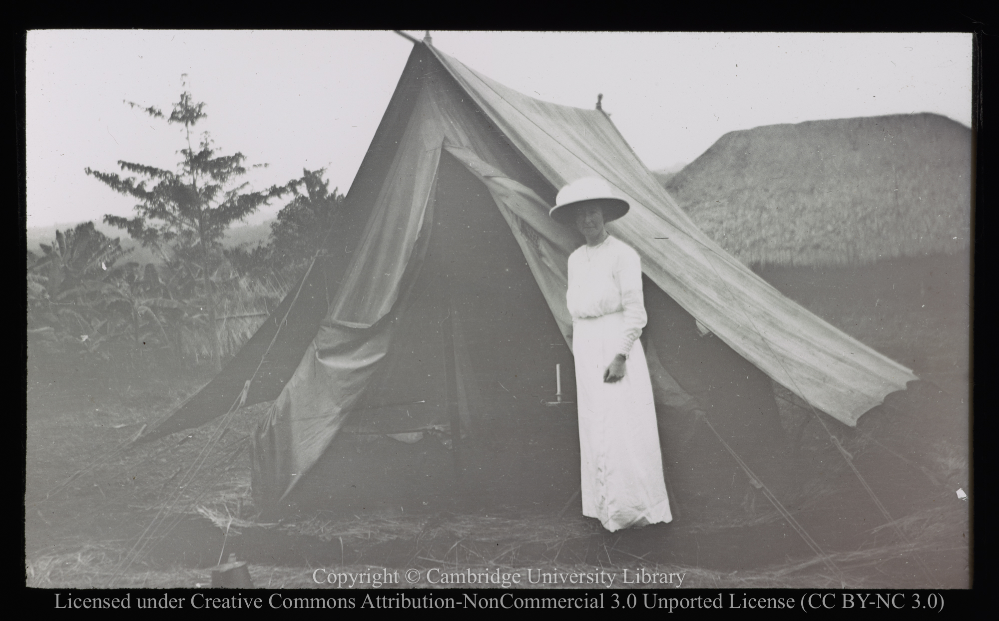 European woman standing by tent, 1905 - 1947