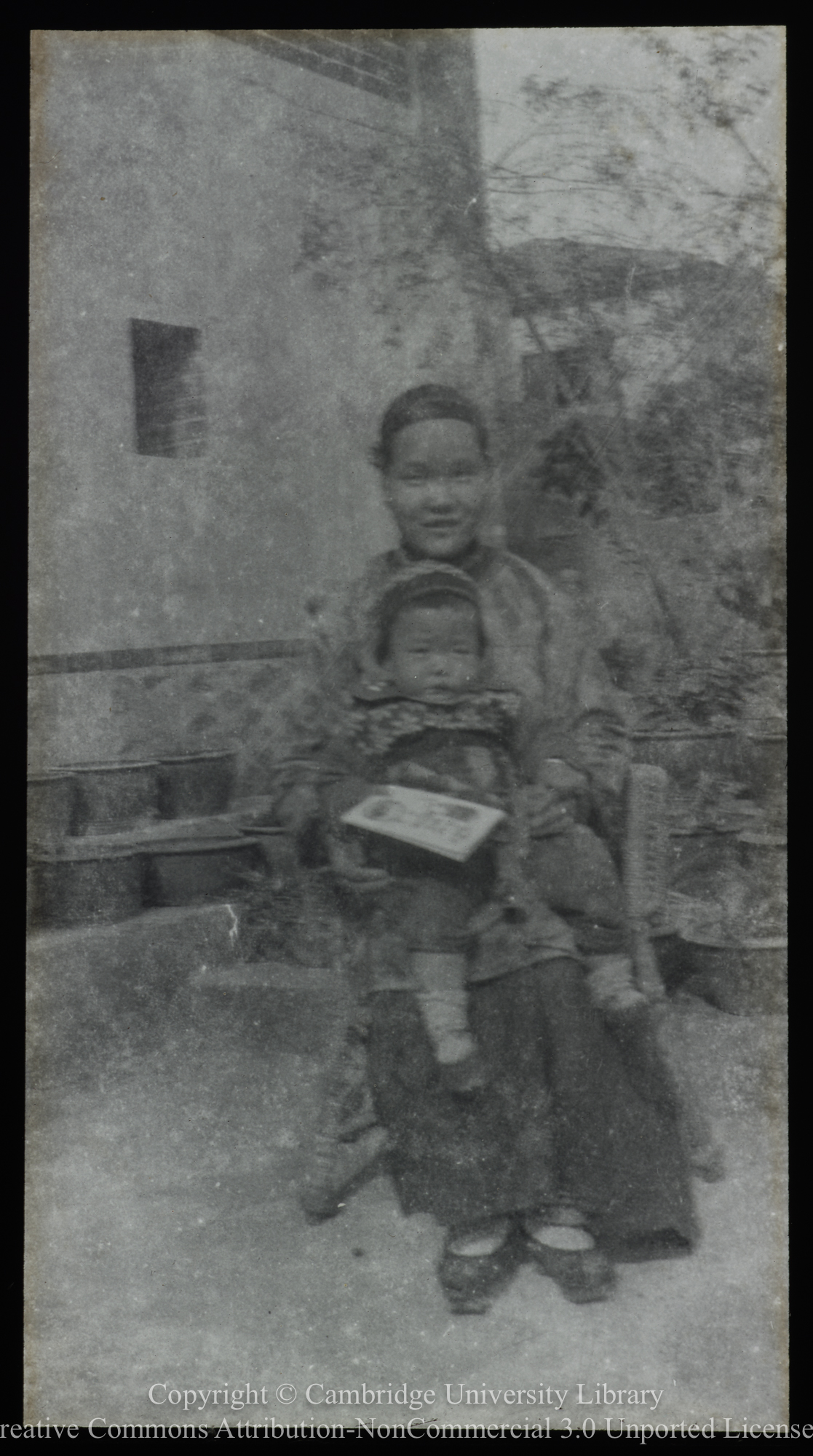 Chinese woman with child on lap, 1900 - 1920