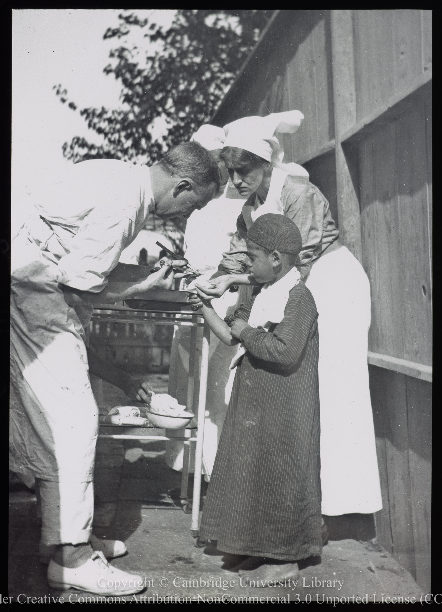 Dr. J.E. Bateman and Nurse E.E. Martin removing a nail from a boy&#39;s hand, 1906 - 1938