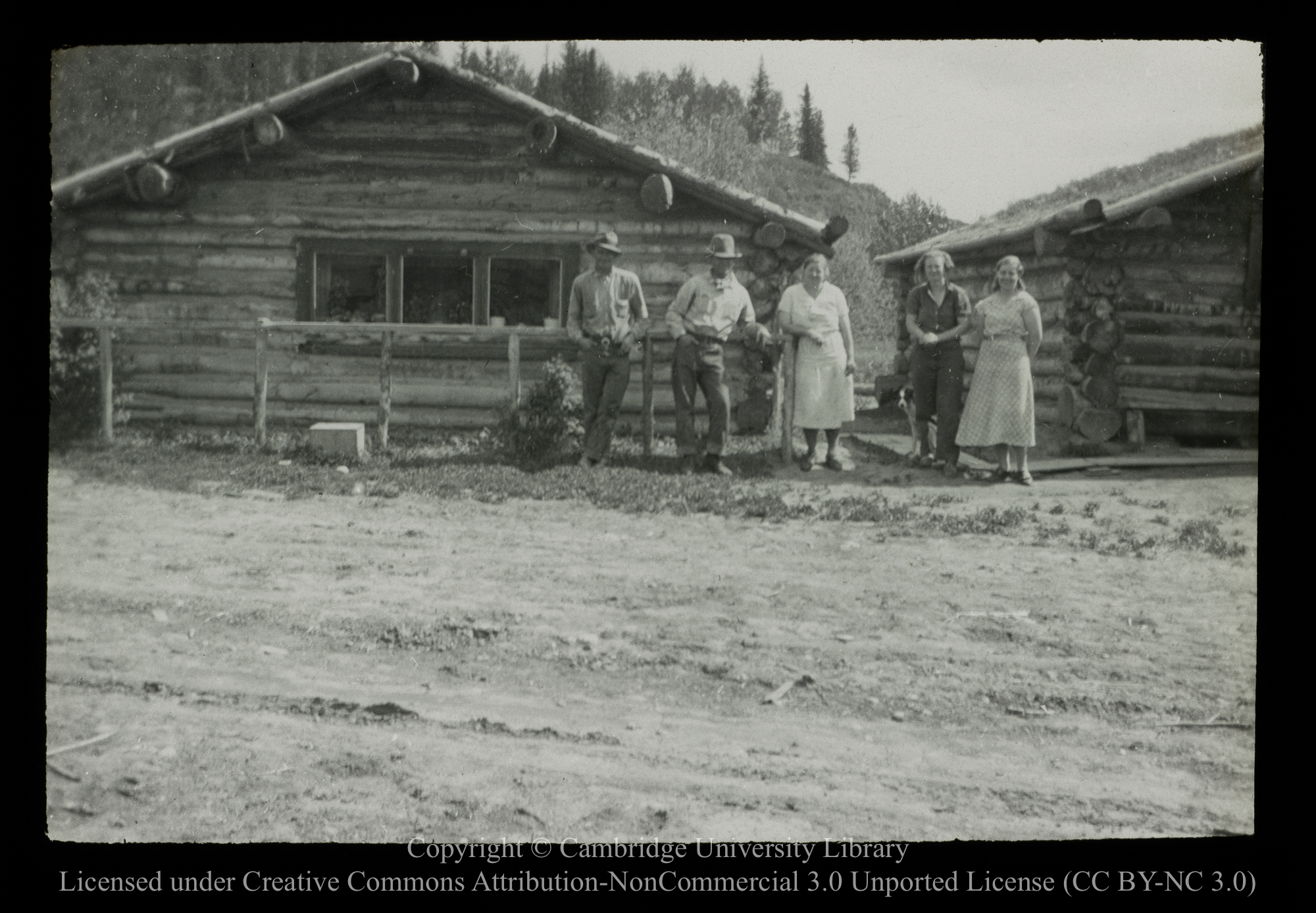 [Settlers by their log cabins], 1910 - 1930